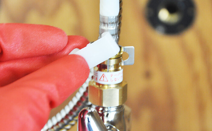 給水ホースと逆止弁の固定キャップを外す