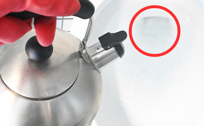 高い位置からトイレの排水口に向かってお湯を流し込む